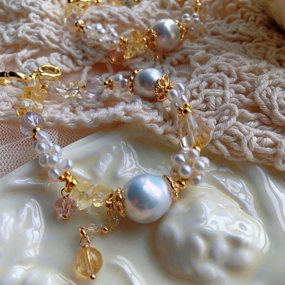 LiraGee baroque pearl bracelet featuring iridescent pearls, seed pearl flower clusters, and warm yellow translucent beads.
