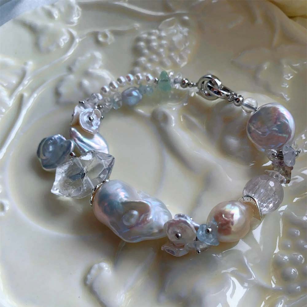 Chunky LiraGee bracelet featuring large iridescent freshwater baroque pearls, raw clear crystal chunks, and carved pearl blossoms.