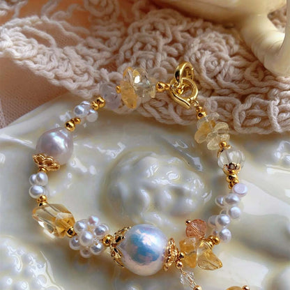 LiraGee baroque pearl bracelet featuring iridescent pearls, seed pearl flower clusters, and warm yellow translucent beads.