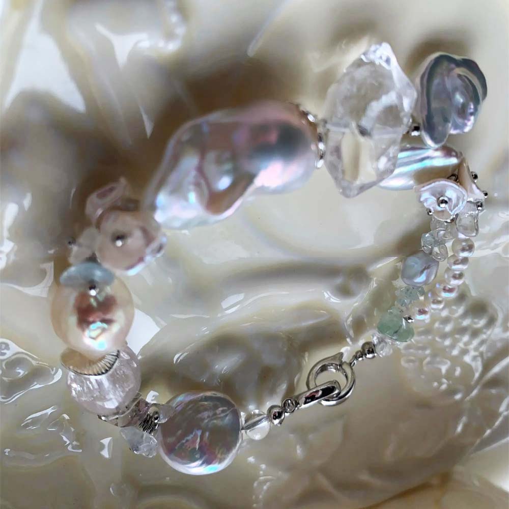 Chunky LiraGee bracelet featuring large iridescent freshwater baroque pearls, raw clear crystal chunks, and carved pearl blossoms.