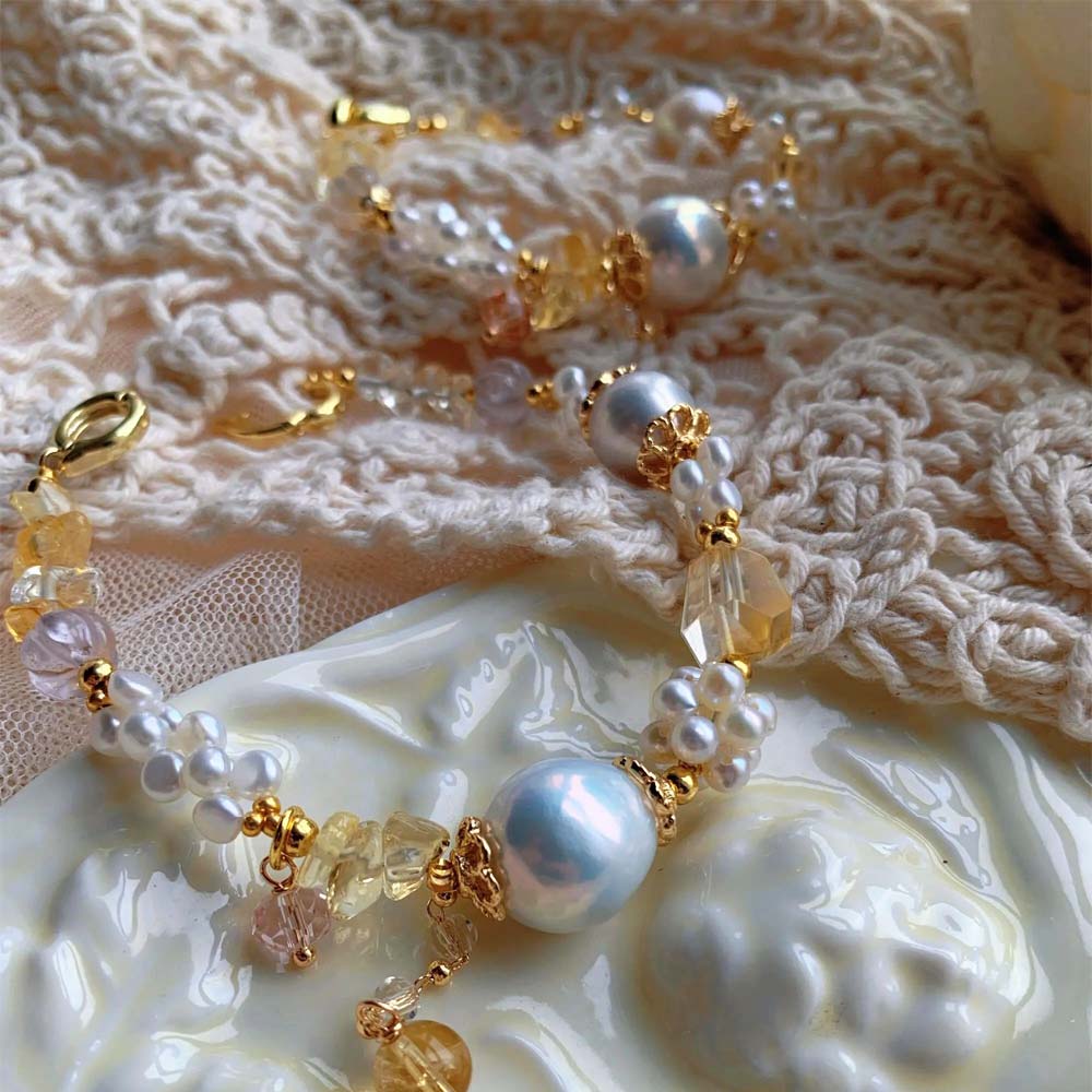 LiraGee baroque pearl bracelet featuring iridescent pearls, seed pearl flower clusters, and warm yellow translucent beads.