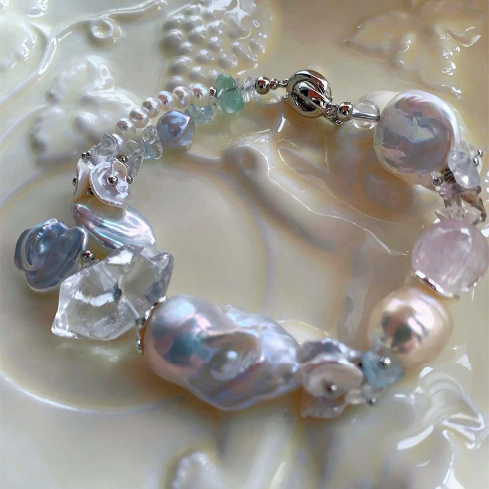 Chunky LiraGee bracelet featuring large iridescent freshwater baroque pearls, raw clear crystal chunks, and carved pearl blossoms.