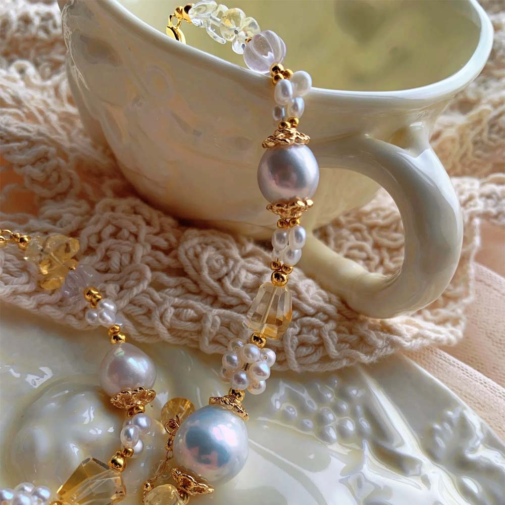 LiraGee baroque pearl bracelet featuring iridescent pearls, seed pearl flower clusters, and warm yellow translucent beads.