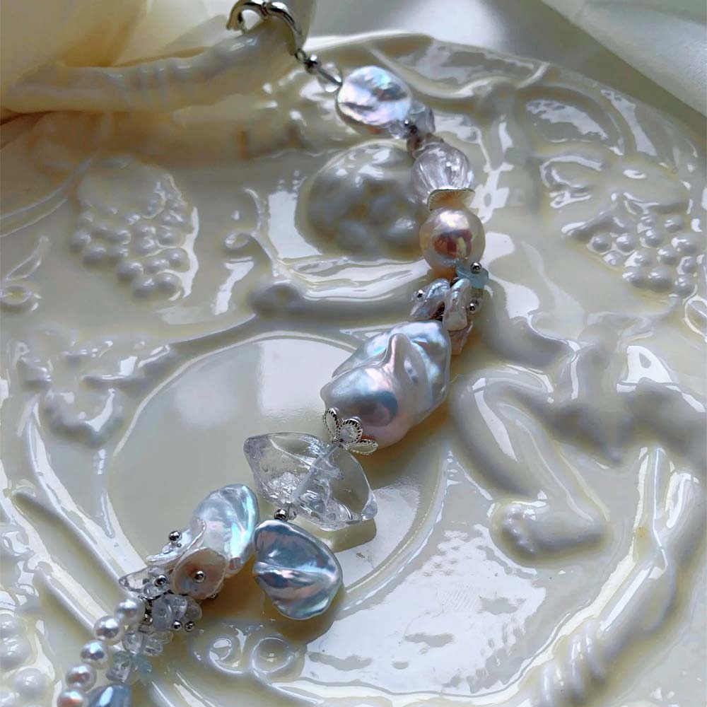 Chunky LiraGee bracelet featuring large iridescent freshwater baroque pearls, raw clear crystal chunks, and carved pearl blossoms.