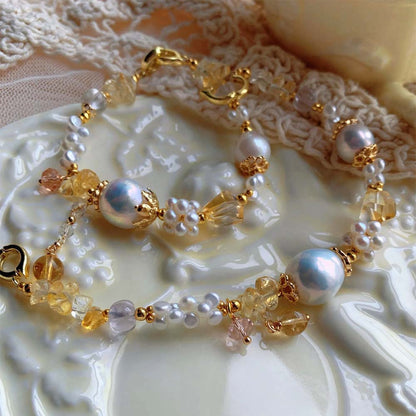 LiraGee baroque pearl bracelet featuring iridescent pearls, seed pearl flower clusters, and warm yellow translucent beads.