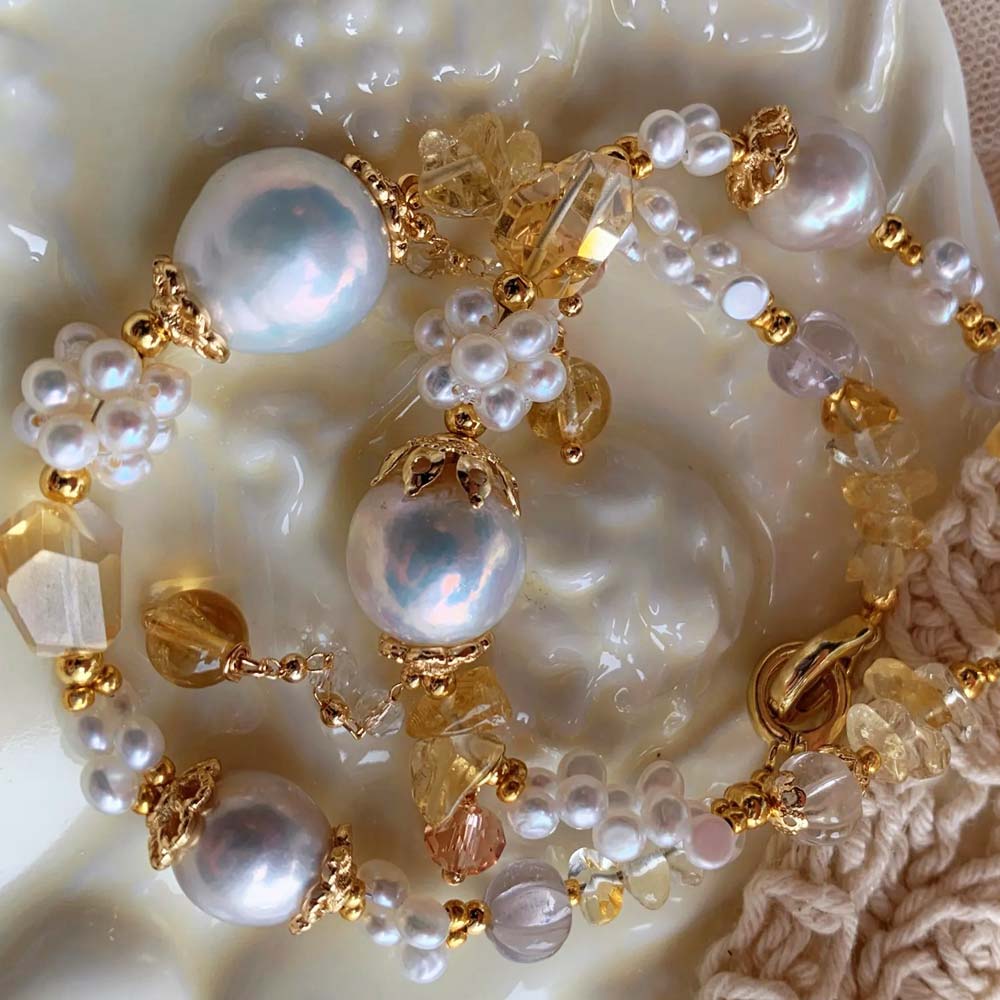 LiraGee baroque pearl bracelet featuring iridescent pearls, seed pearl flower clusters, and warm yellow translucent beads.