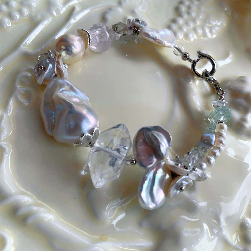 Chunky LiraGee bracelet featuring large iridescent freshwater baroque pearls, raw clear crystal chunks, and carved pearl blossoms.
