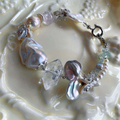 Chunky LiraGee bracelet featuring large iridescent freshwater baroque pearls, raw clear crystal chunks, and carved pearl blossoms.