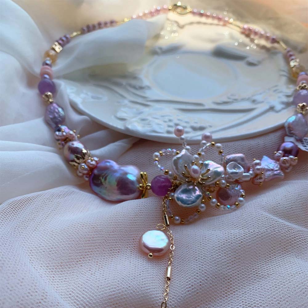 Lavender and pink freshwater baroque pearl necklace featuring a central floral motif and pearl pendant drop.
