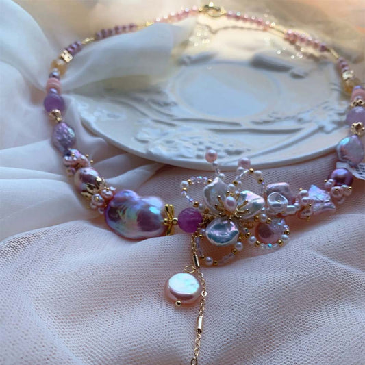 Lavender and pink freshwater baroque pearl necklace featuring a central floral motif and pearl pendant drop.