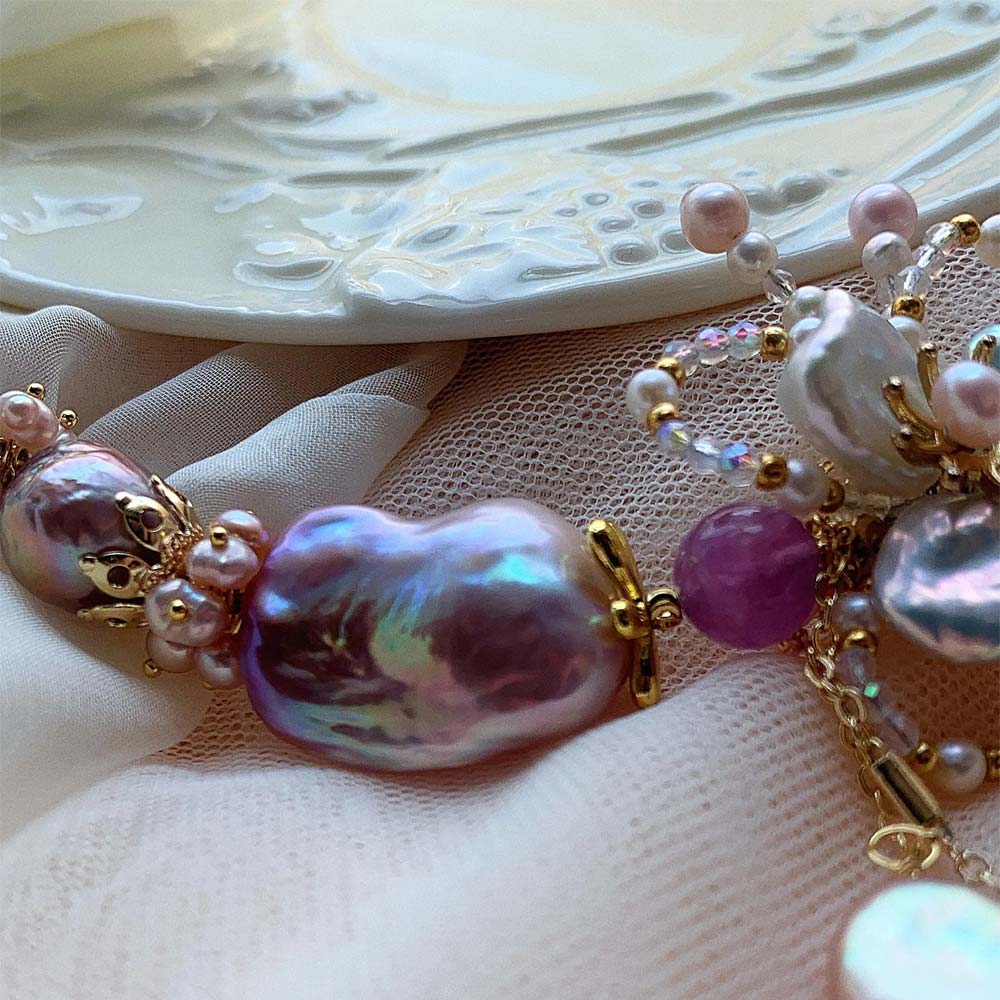 Lavender and pink freshwater baroque pearl necklace featuring a central floral motif and pearl pendant drop.